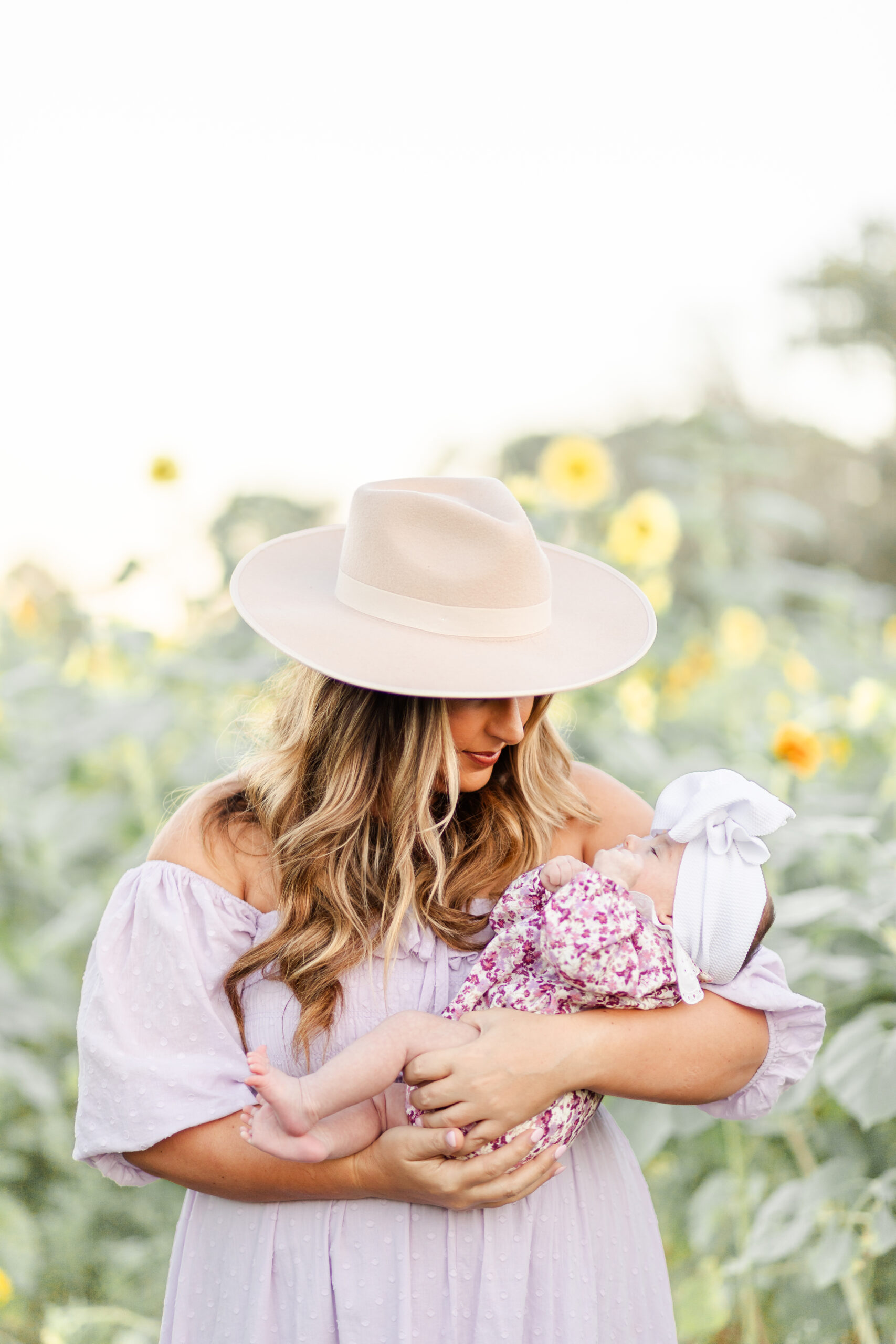 mom and newborn in sunflower field